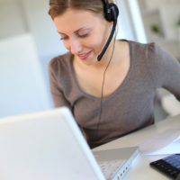 Young woman working from home with laptop and headset
